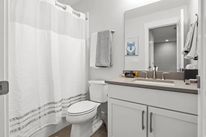 Full bath with a shower with curtain, vanity, and dark tile patterned floors