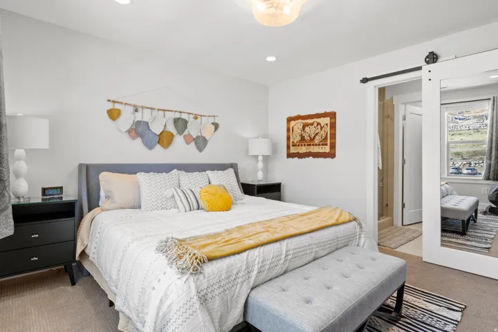 Carpeted bedroom with a barn door, recessed lighting, and ensuite bath