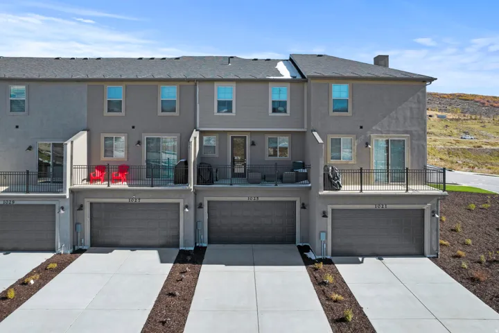 Rear view of property with a balcony, stucco siding, and an attached garage