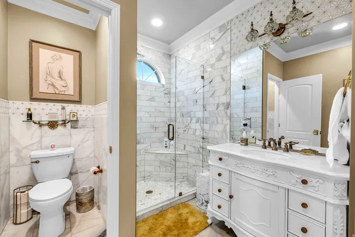Bathroom featuring a stall shower, vanity, crown molding, and tile walls