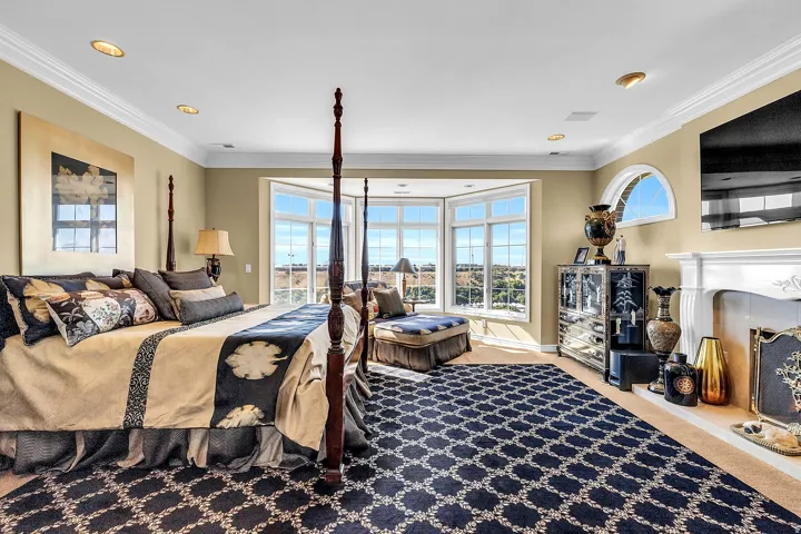 Bedroom with a fireplace, light carpet, ornamental molding, multiple windows, and access to outside