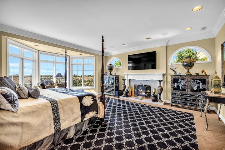 Bedroom featuring ornamental molding, a lit fireplace, and light colored carpet
