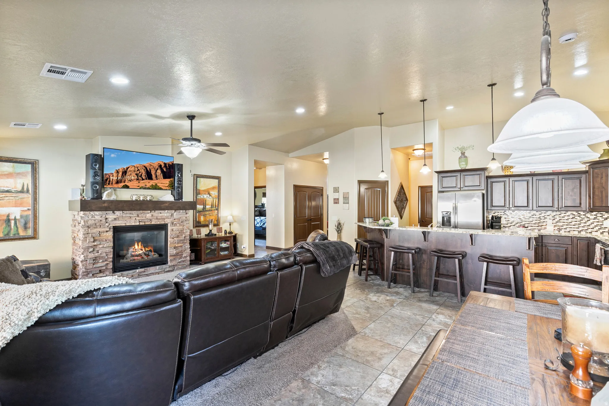 Living area featuring ceiling fan, lofted ceiling, a stone fireplace, and recessed lighting