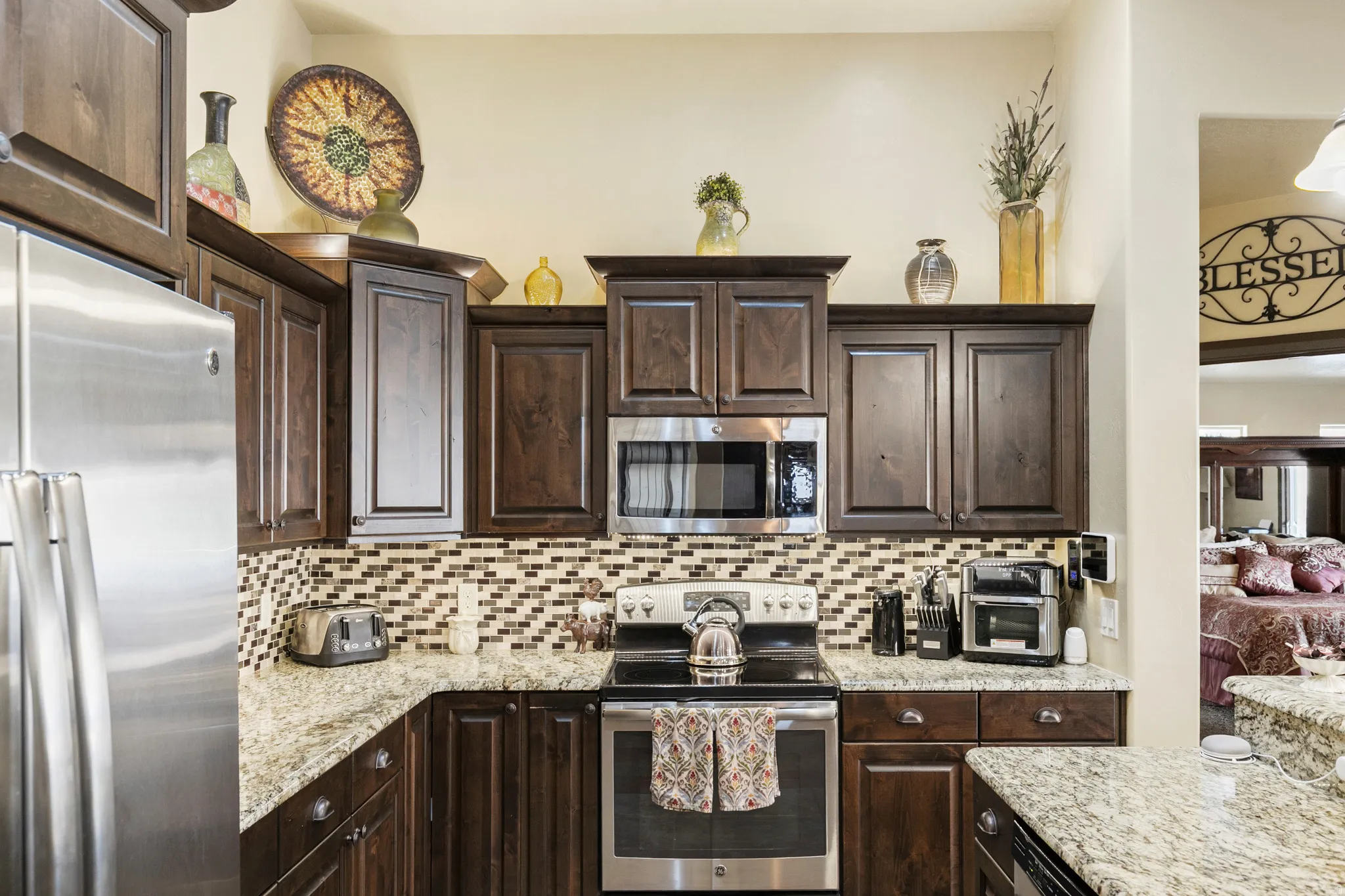 Kitchen featuring dark wood finish cabinets, stainless steel appliances, light stone countertops, and backsplash
