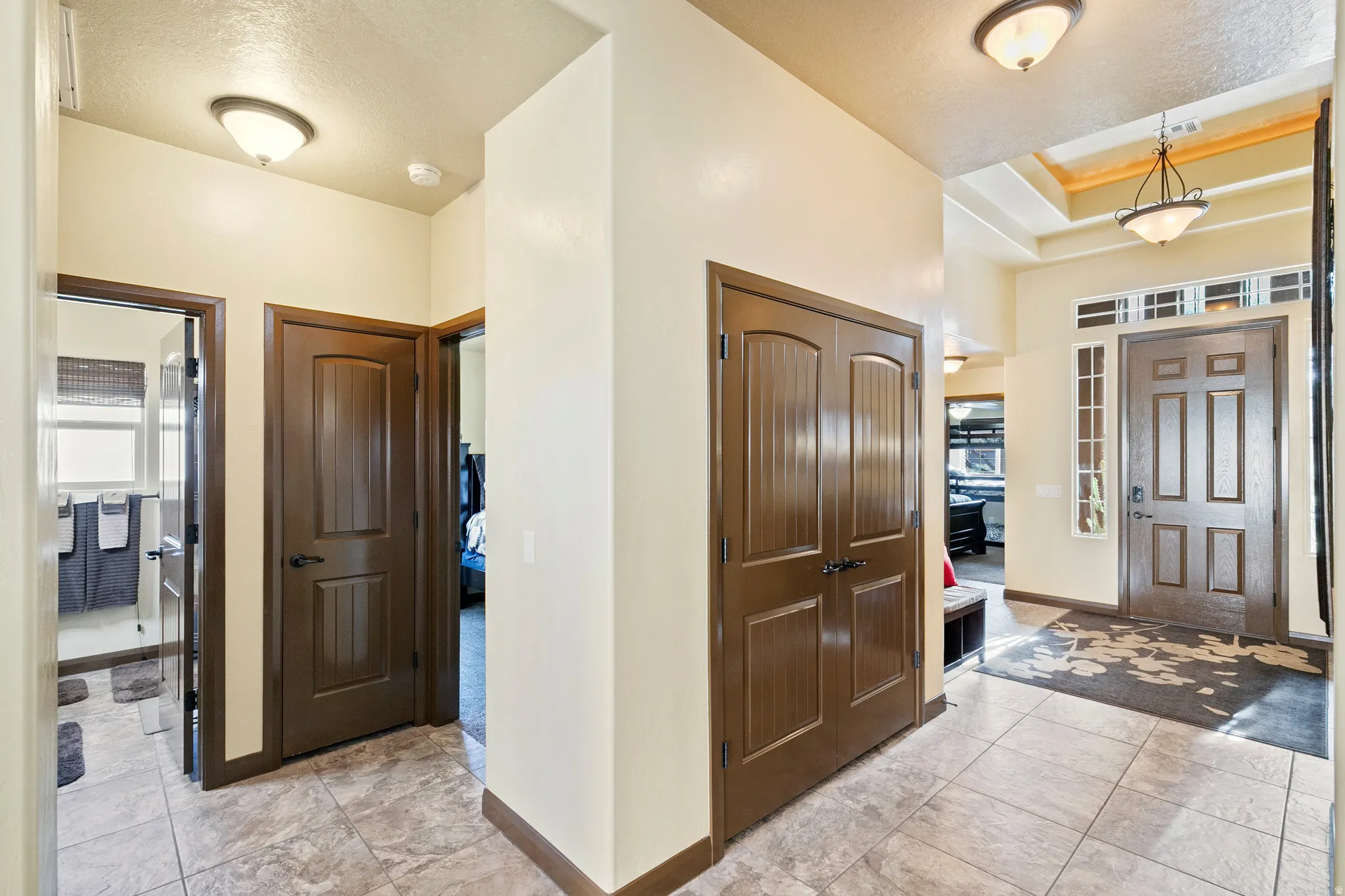 Foyer with light tile patterned floors and a tray ceiling