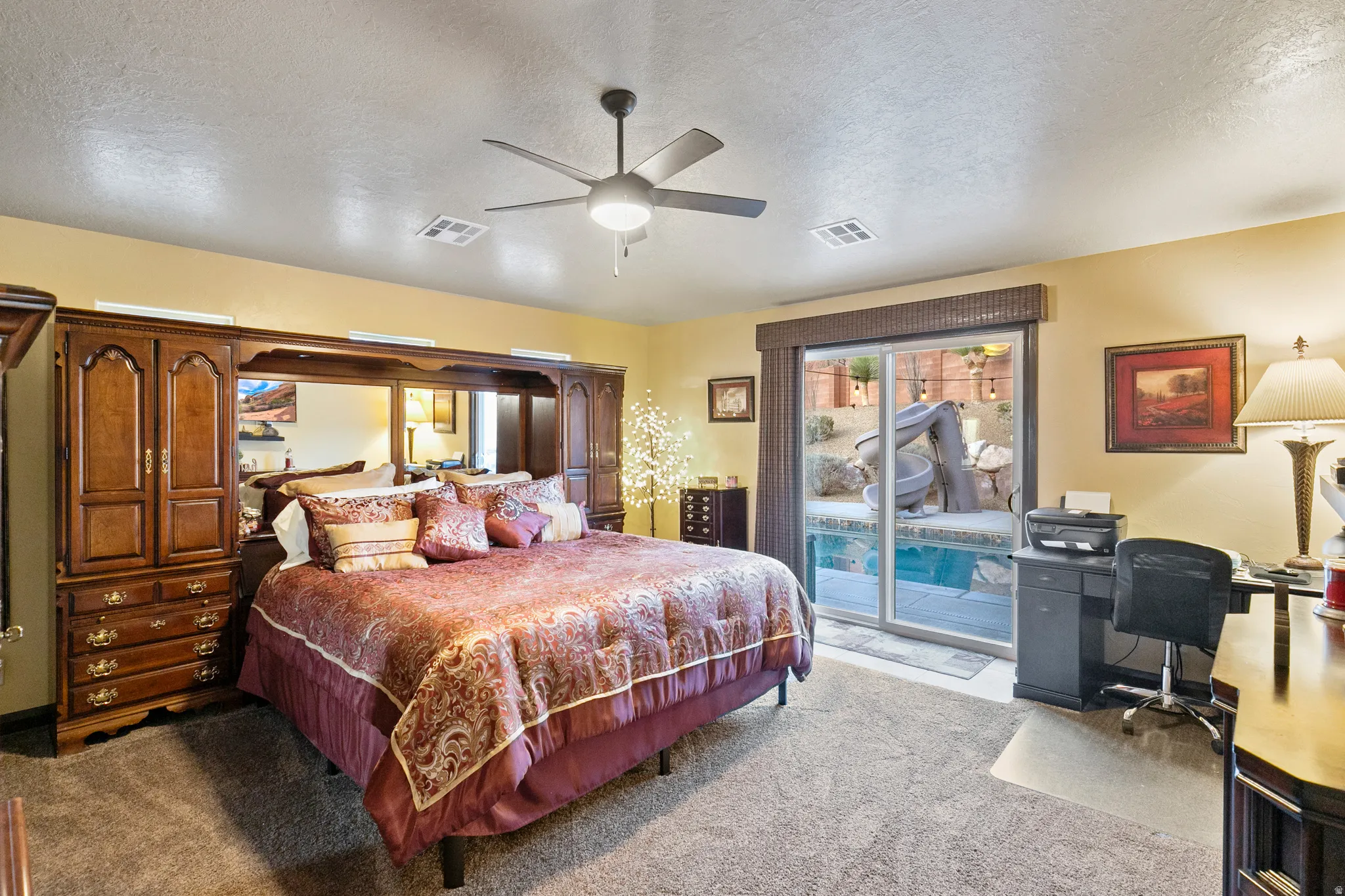 Bedroom with a textured ceiling, access to outside, light carpet, an office area, and a ceiling fan