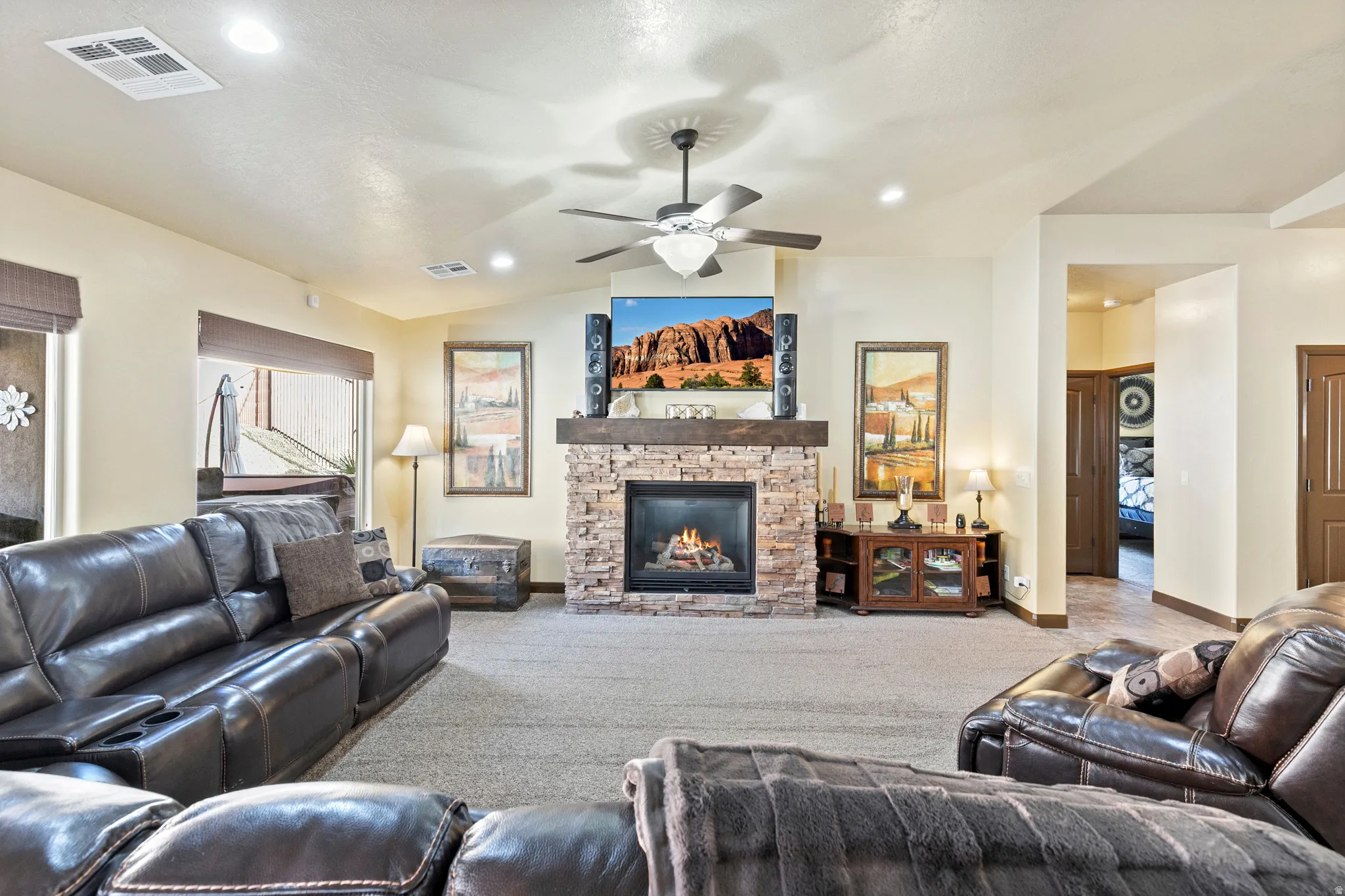 Carpeted living area with a fireplace and a ceiling fan