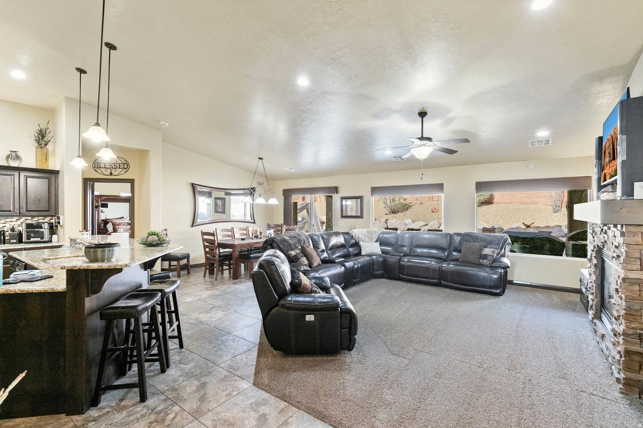 Living area with a stone fireplace, a ceiling fan, lofted ceiling, recessed lighting, and light carpet