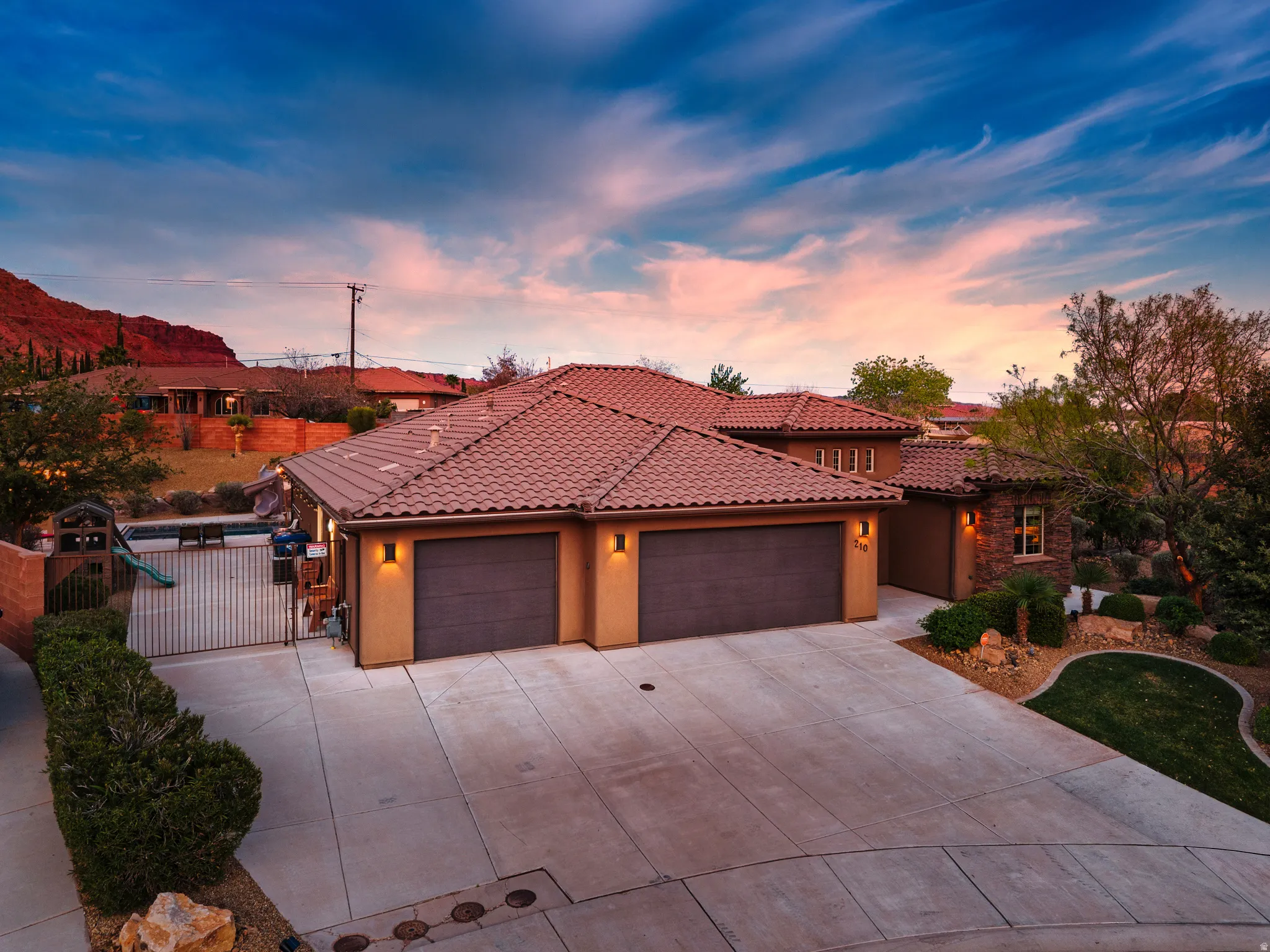 Mediterranean / spanish home featuring a garage, driveway, stucco siding, and a gate