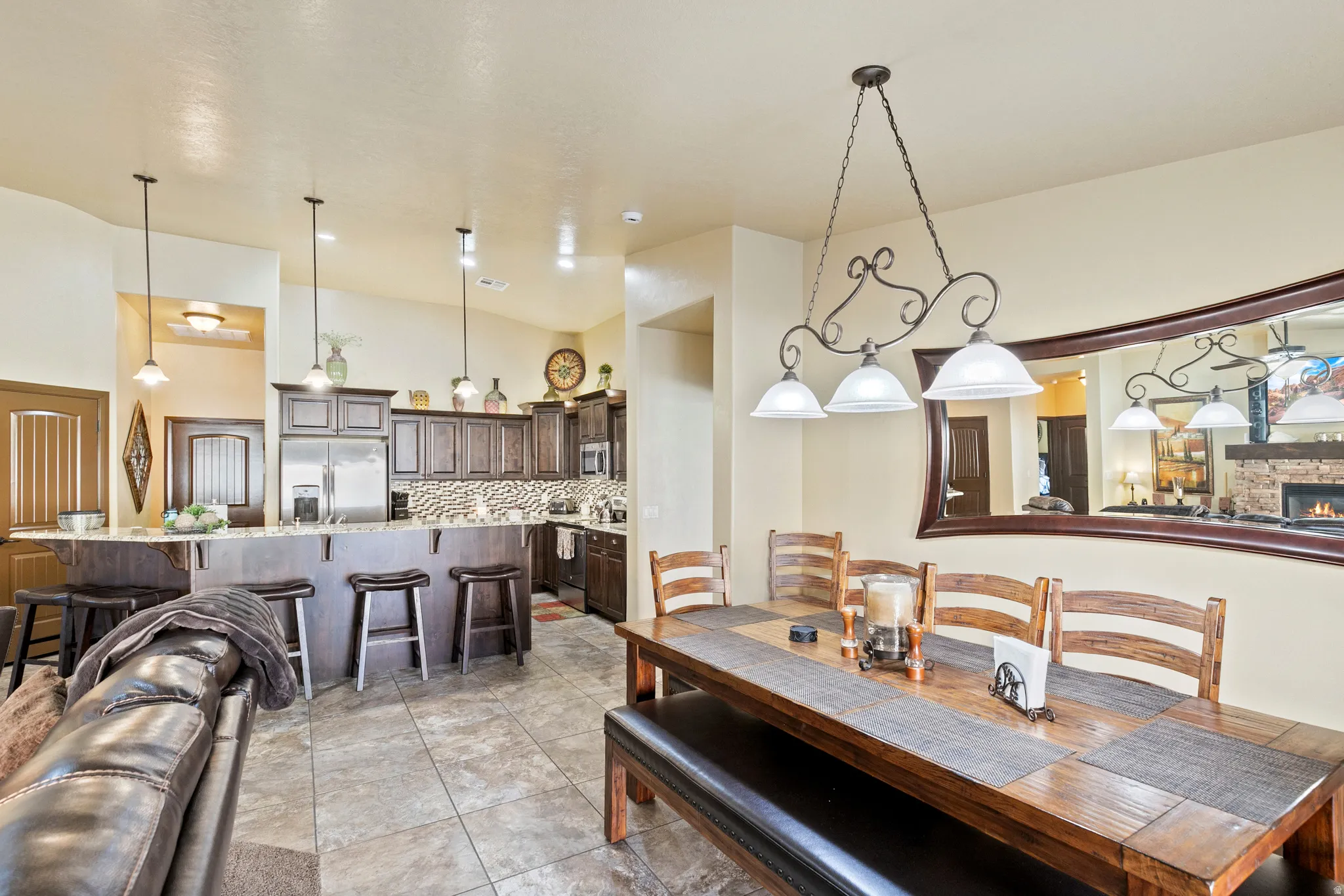 Dining room with a high ceiling, a stone fireplace, and light tile patterned flooring