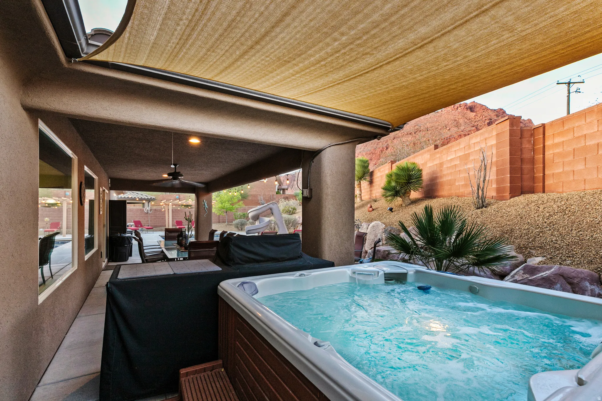 Fenced backyard with a patio area, a ceiling fan, a hot tub, and area for grilling