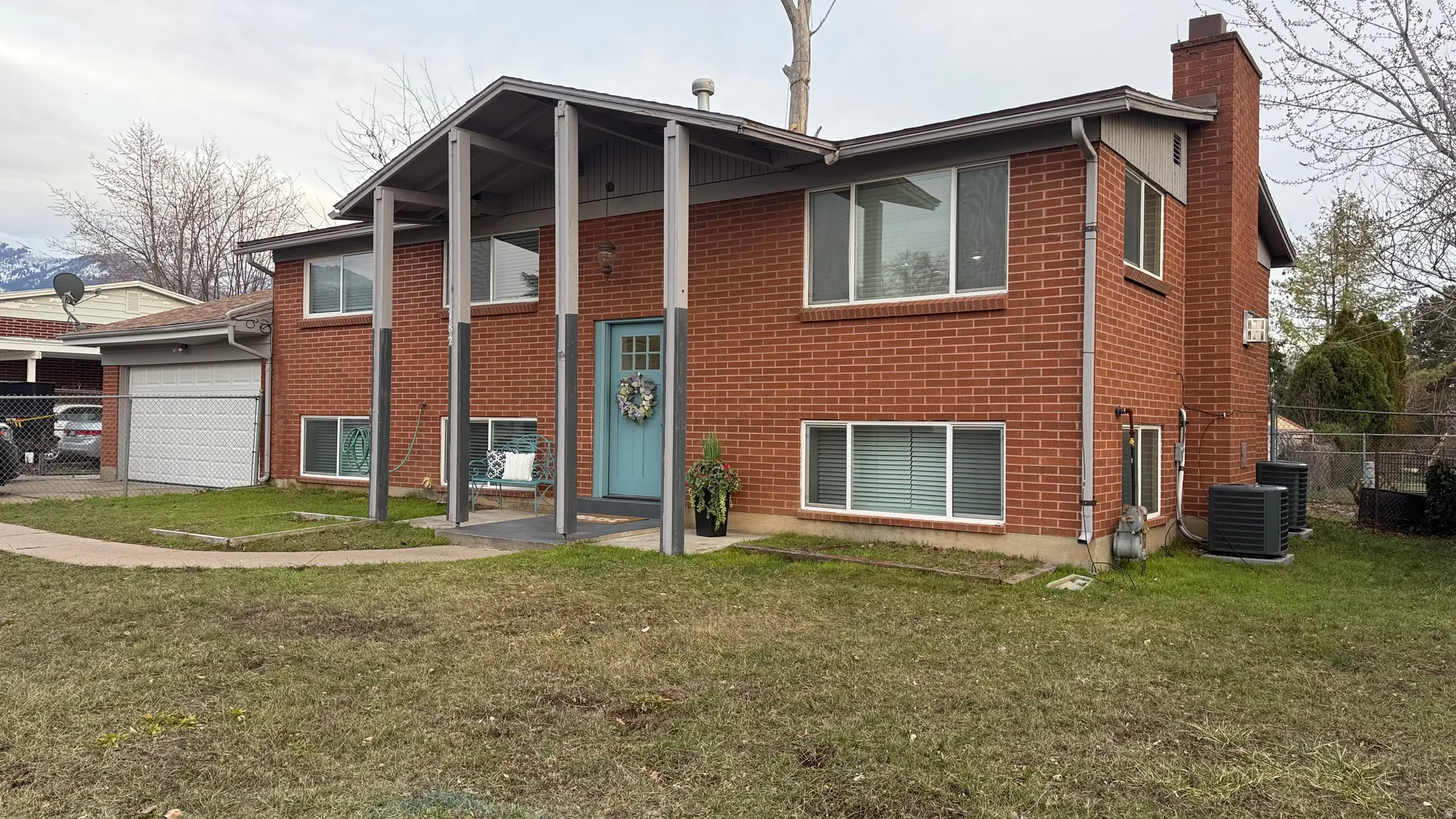 Raised ranch featuring a chimney, brick siding, and a garage