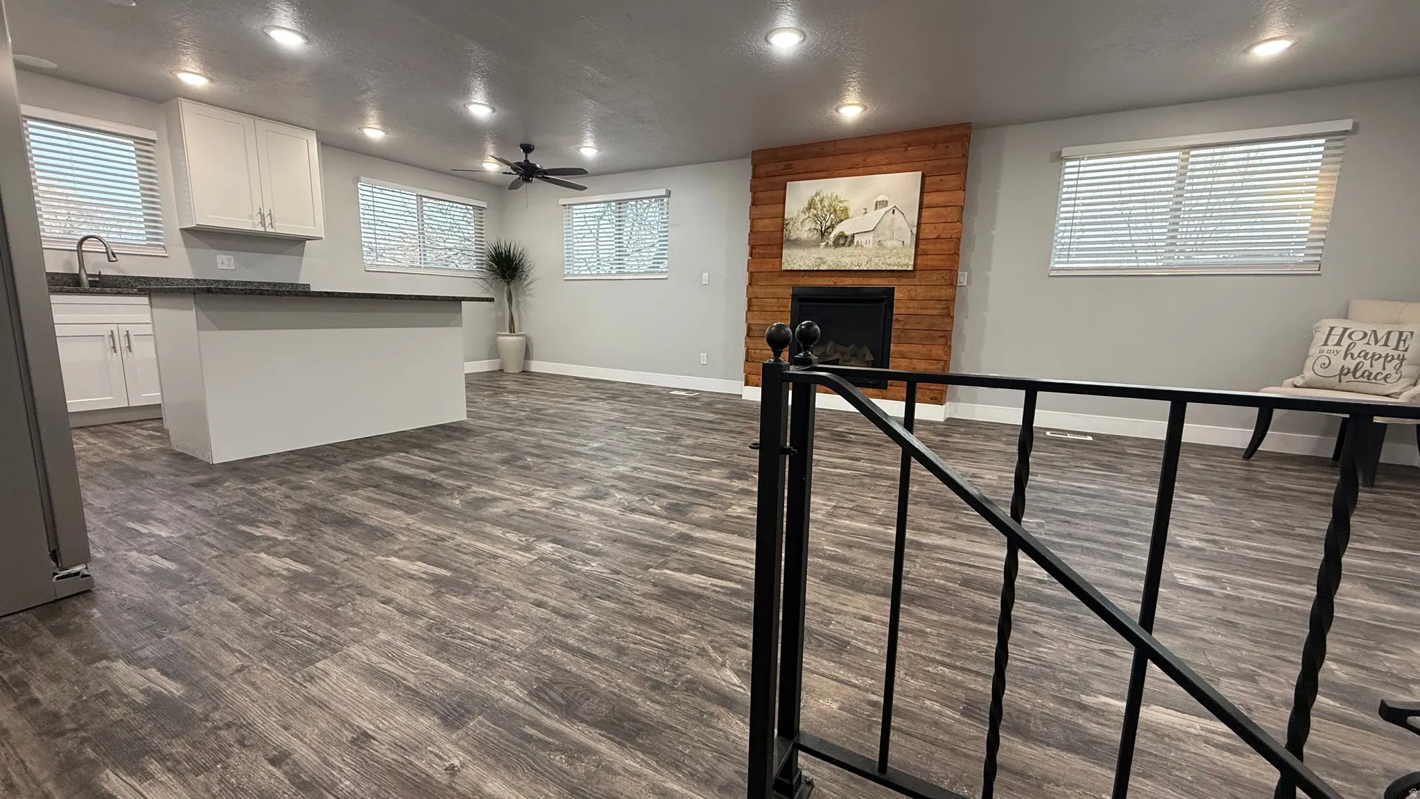 Living area featuring a ceiling fan, a large fireplace, dark wood-style flooring, recessed lighting, and a textured ceiling