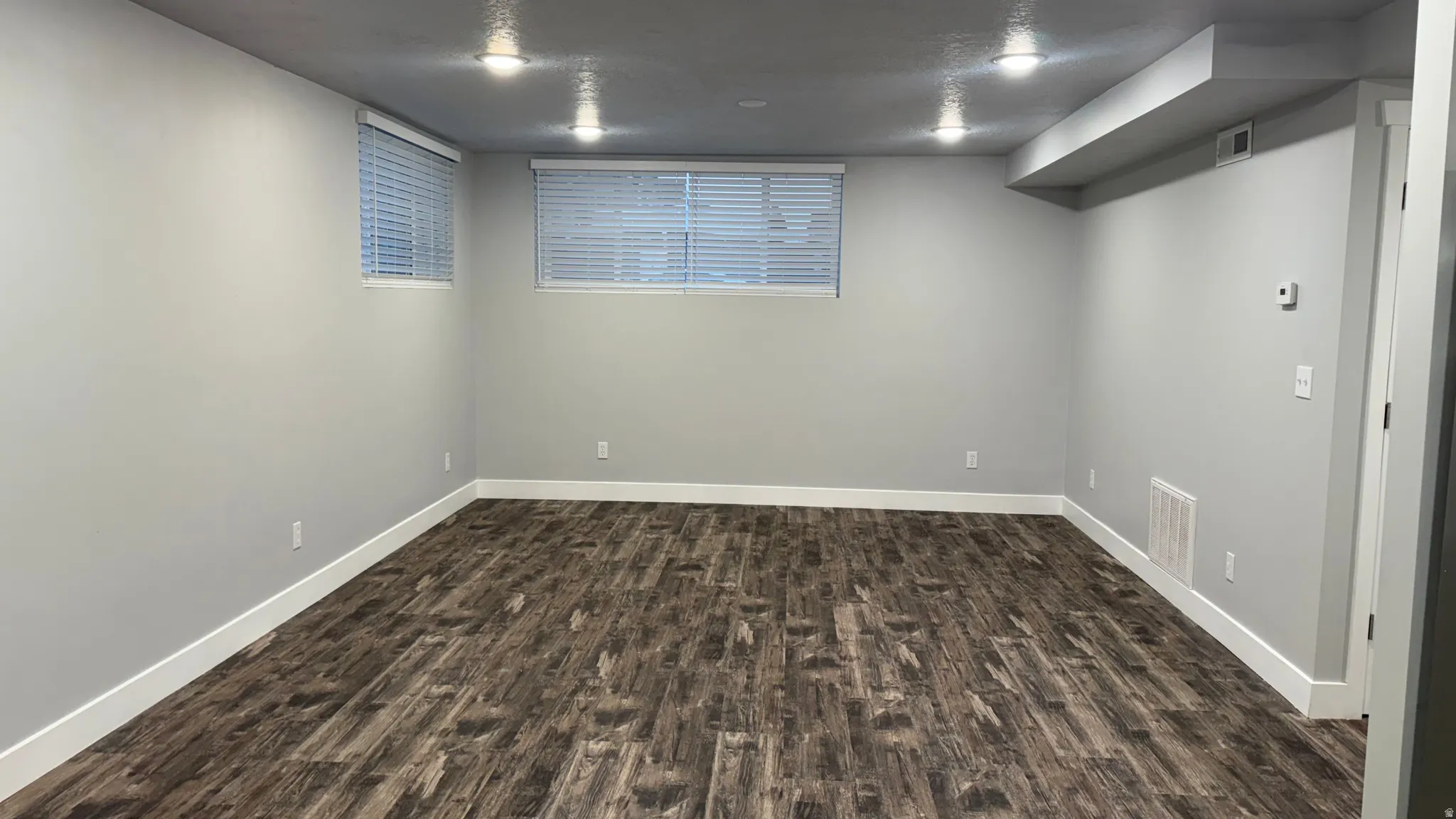 Finished basement featuring dark wood-style flooring and a textured ceiling