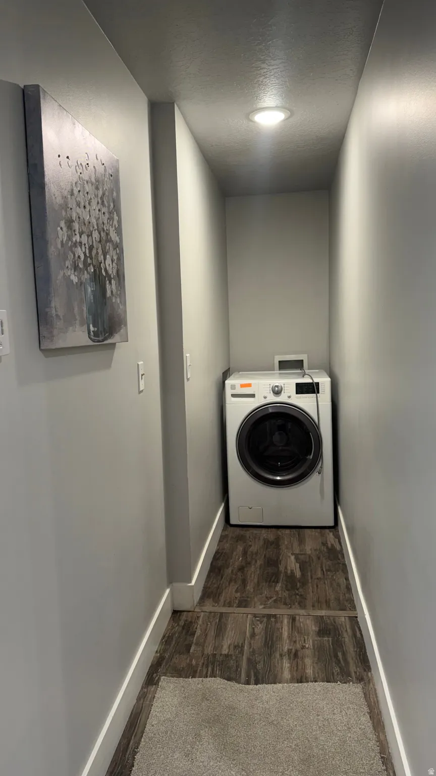 Laundry area with washer / dryer, dark wood finished floors, and a textured ceiling
