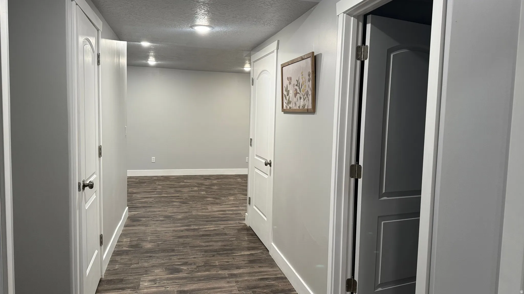 Hall with a textured ceiling and dark wood-type flooring
