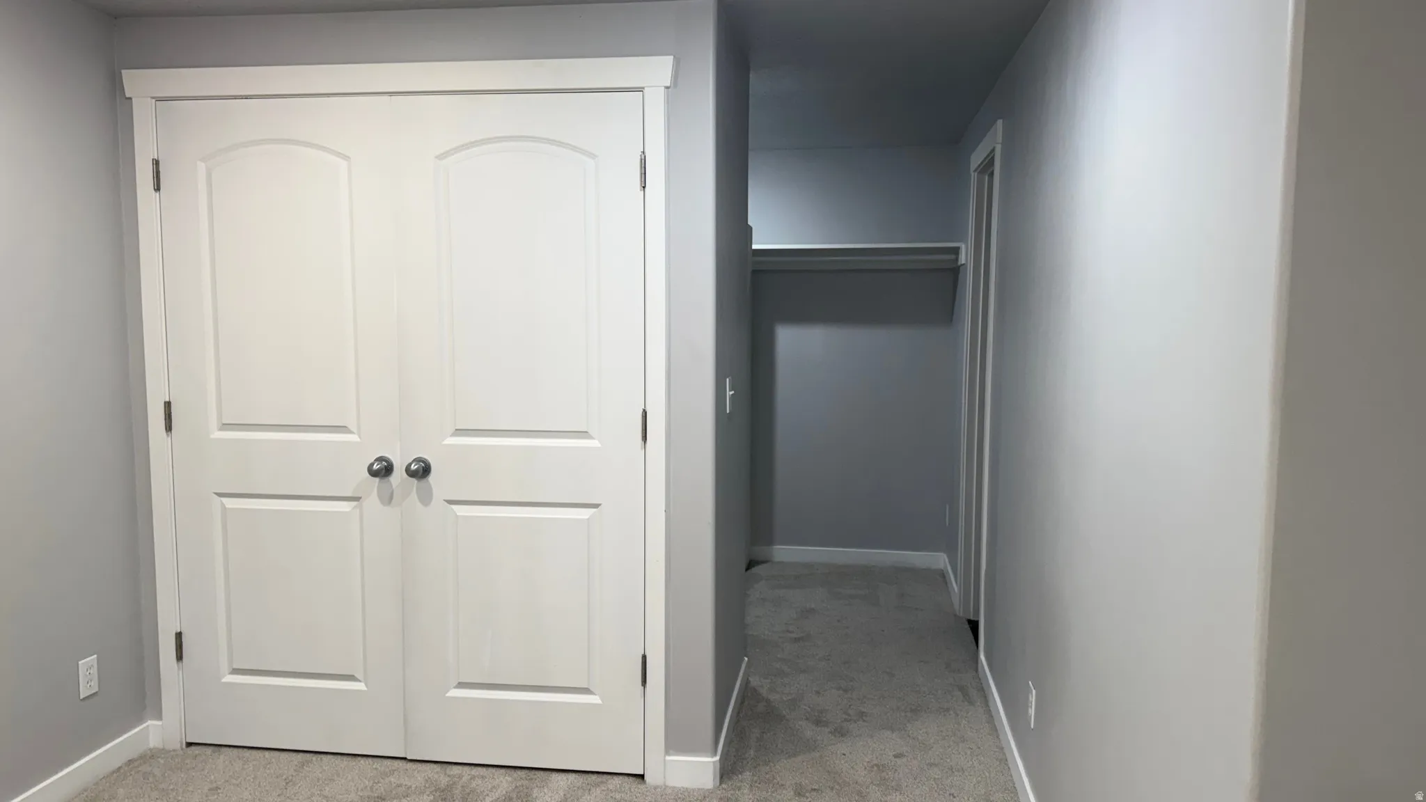 Hall with light colored carpet and baseboards