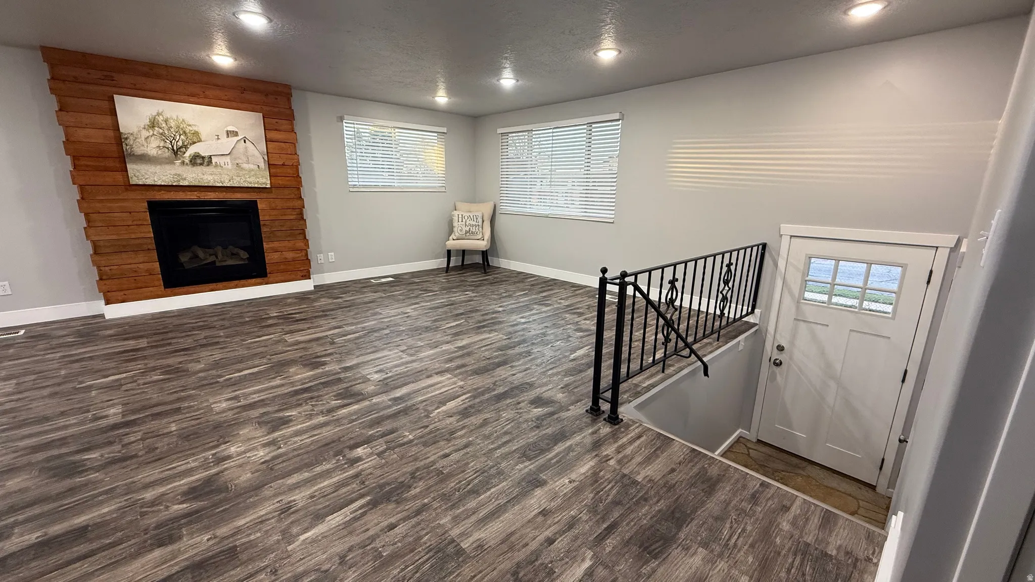 Entrance foyer with a large fireplace, dark wood-type flooring, a textured ceiling, and recessed lighting