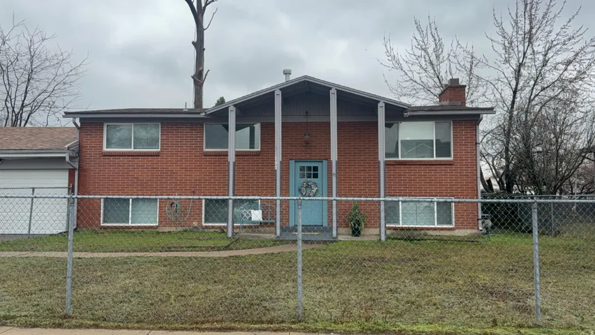 Back of house with a garage, a chimney, and brick siding