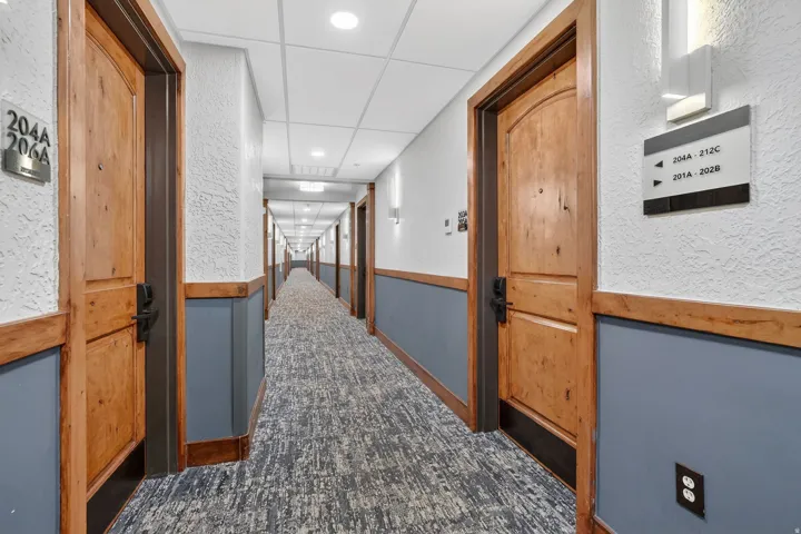 Corridor with a textured wall, dark colored carpet, and recessed lighting