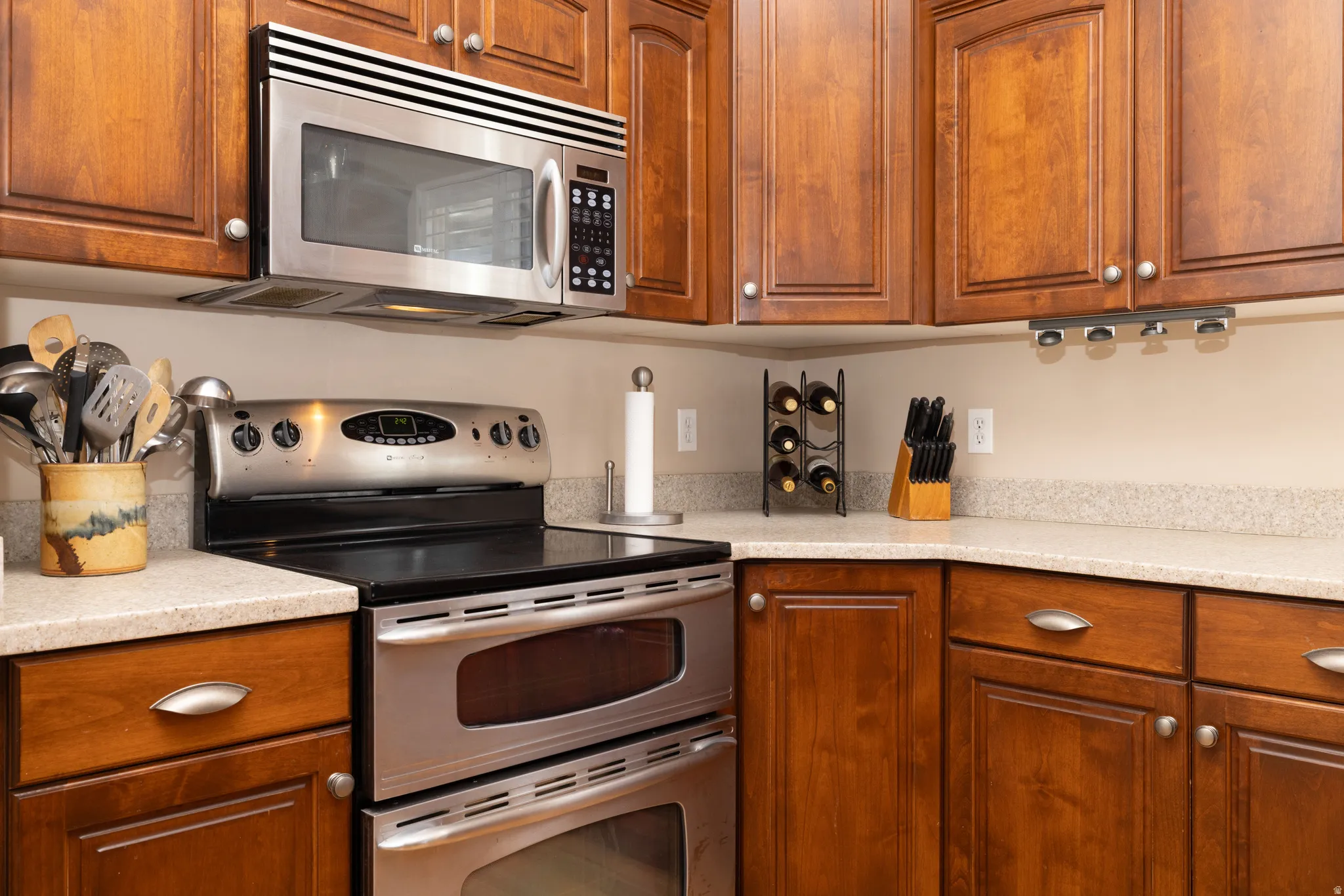 Kitchen featuring stainless steel appliances, wood finish cabinetry, and light stone countertops