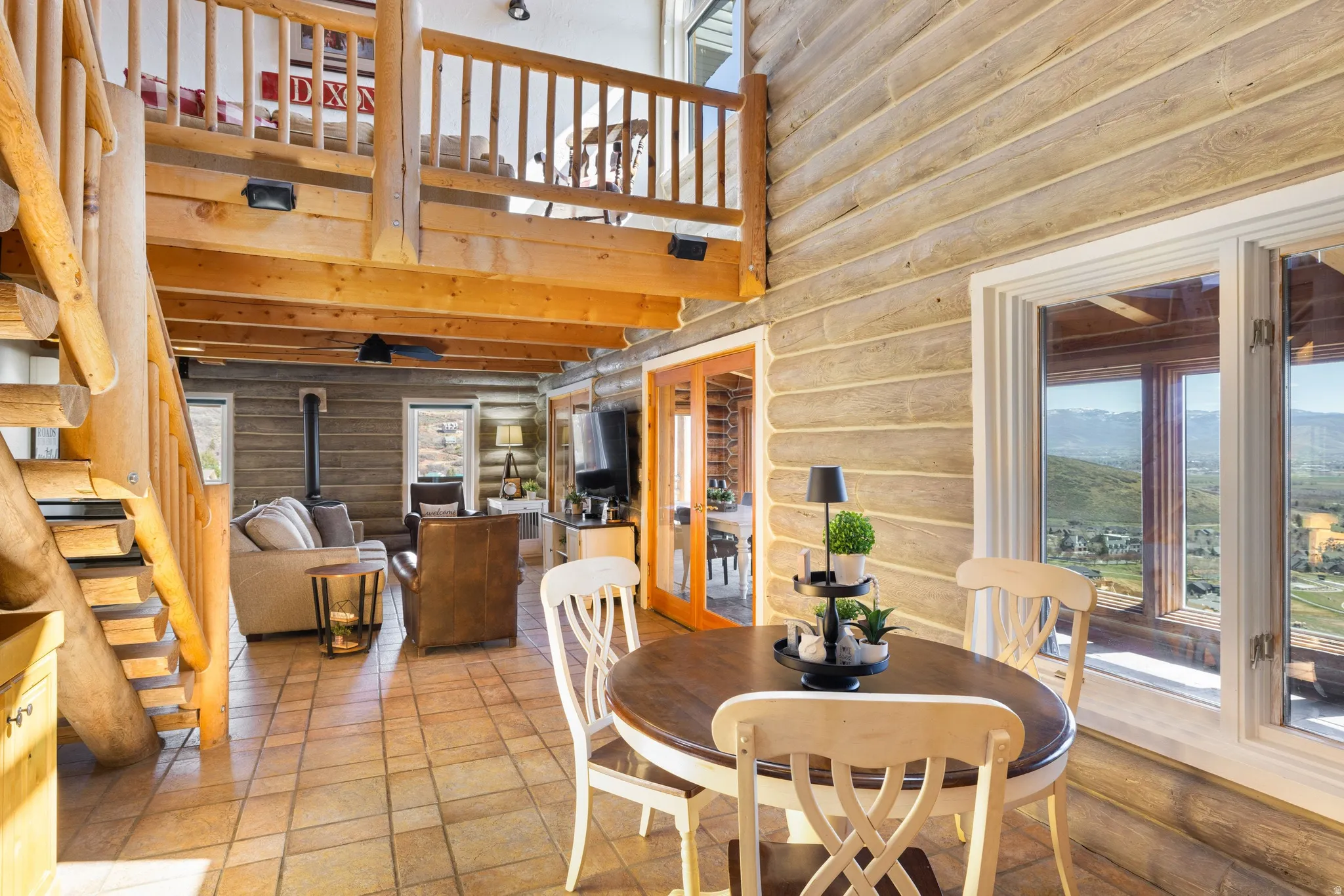 Dining space with a wood stove, a high ceiling, and log walls