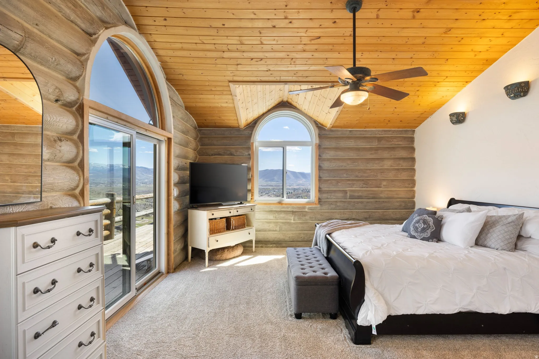 Carpeted bedroom with rustic walls, a vaulted wood ceiling, access to outside, and ceiling fan