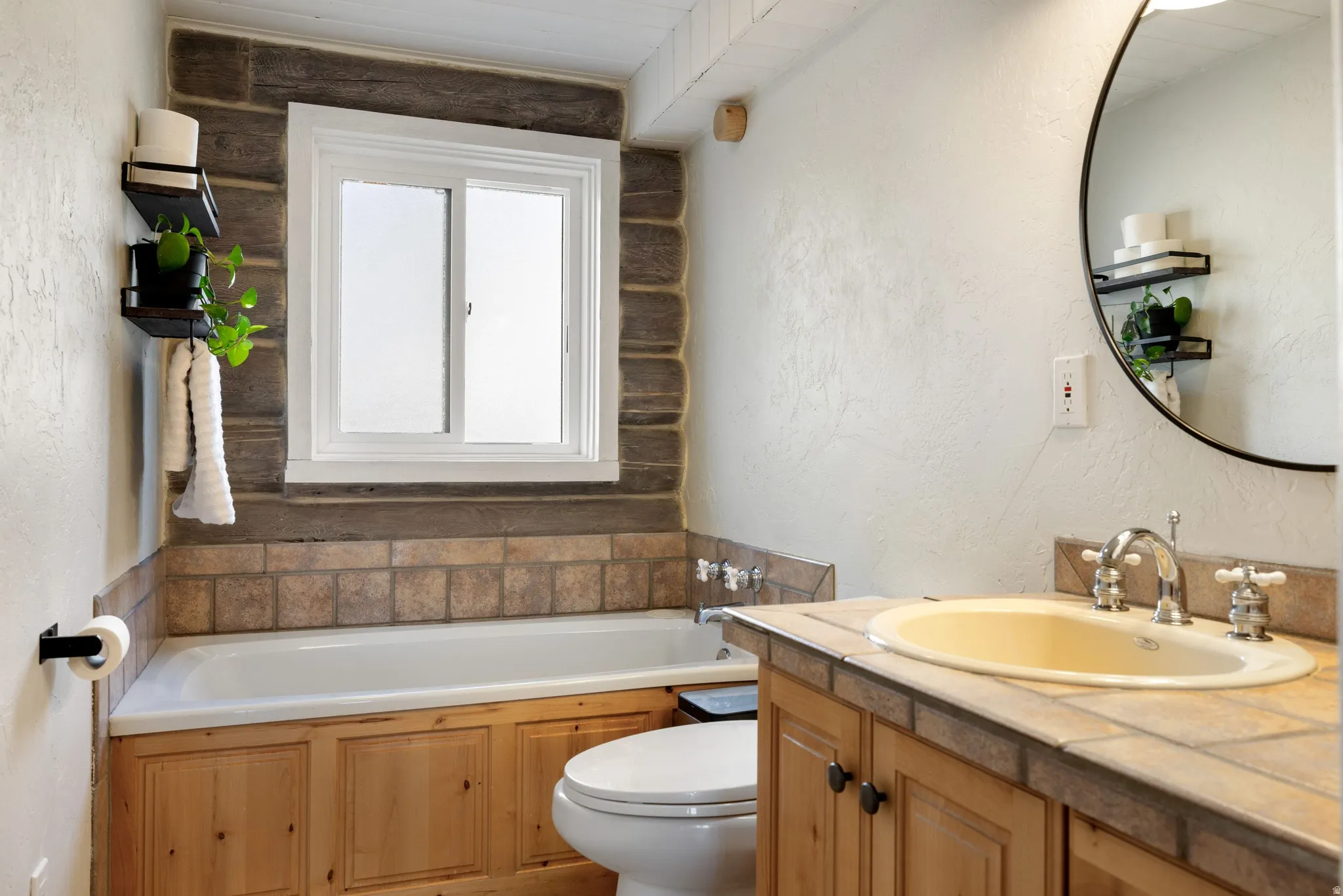 Bathroom featuring a textured wall, a garden tub, and vanity