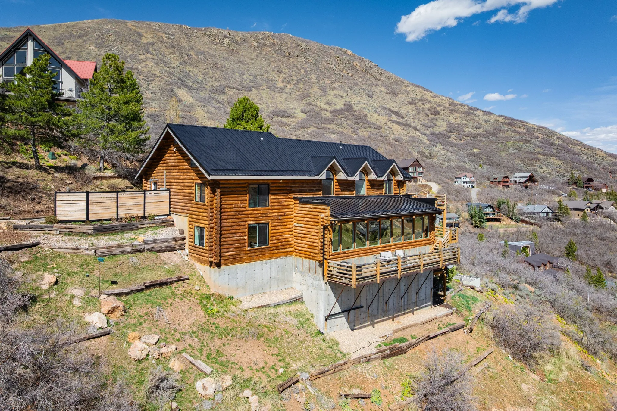 Rear view of house featuring log exterior, a mountain view, a metal roof, and a sunroom