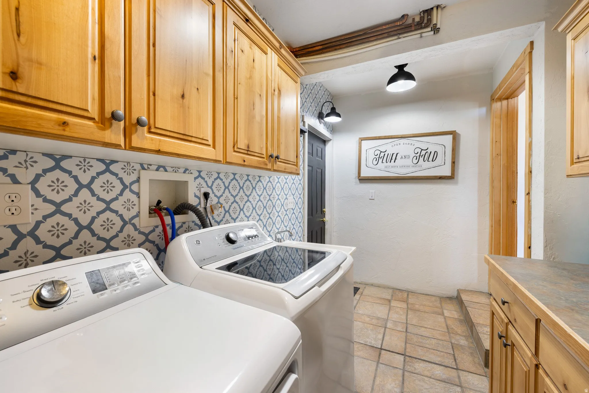 Laundry room featuring cabinet space, washing machine and clothes dryer, and light stone finish floors