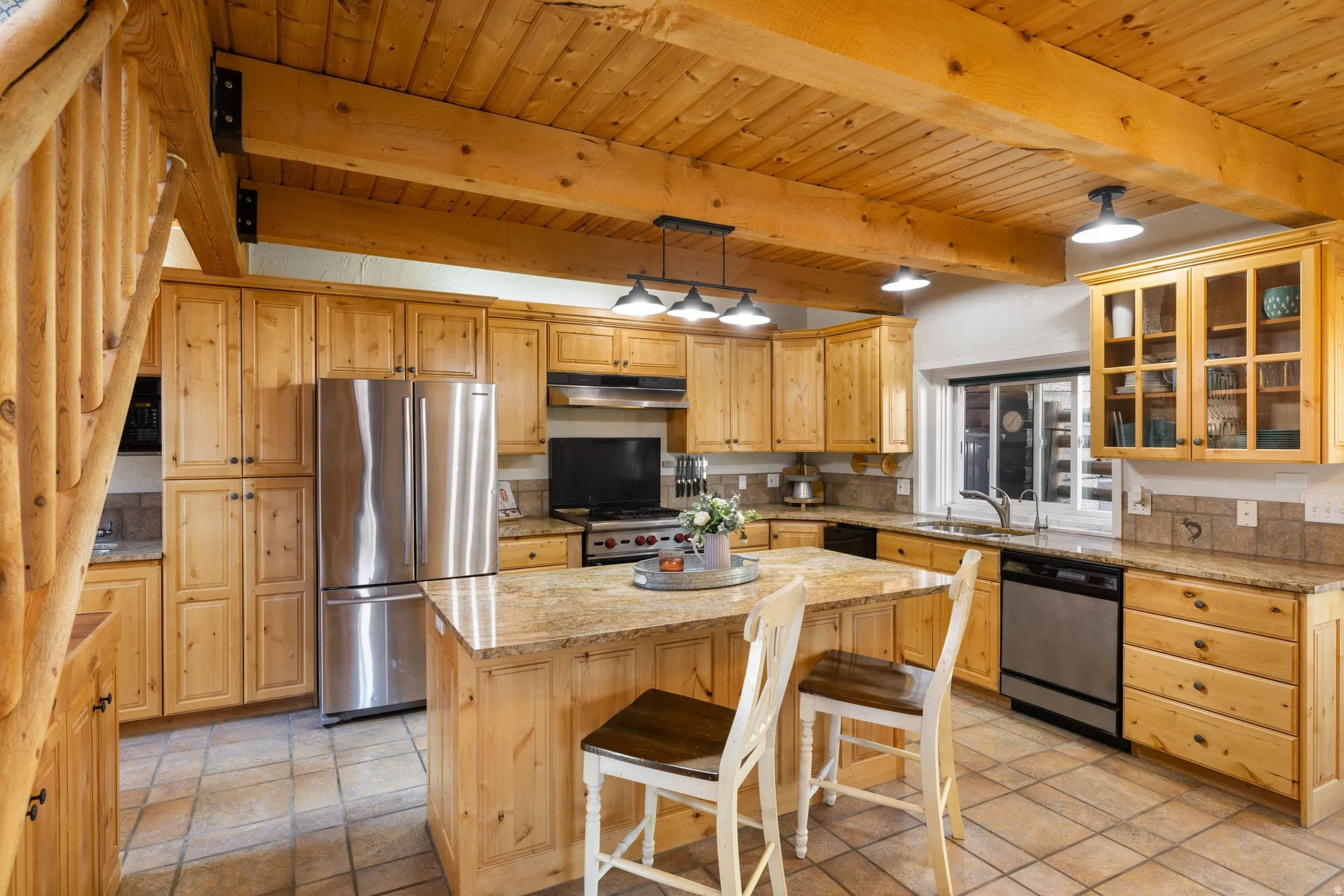 Kitchen featuring glass insert cabinets, stainless steel appliances, a kitchen island, light stone counters, and light wood finish cabinets