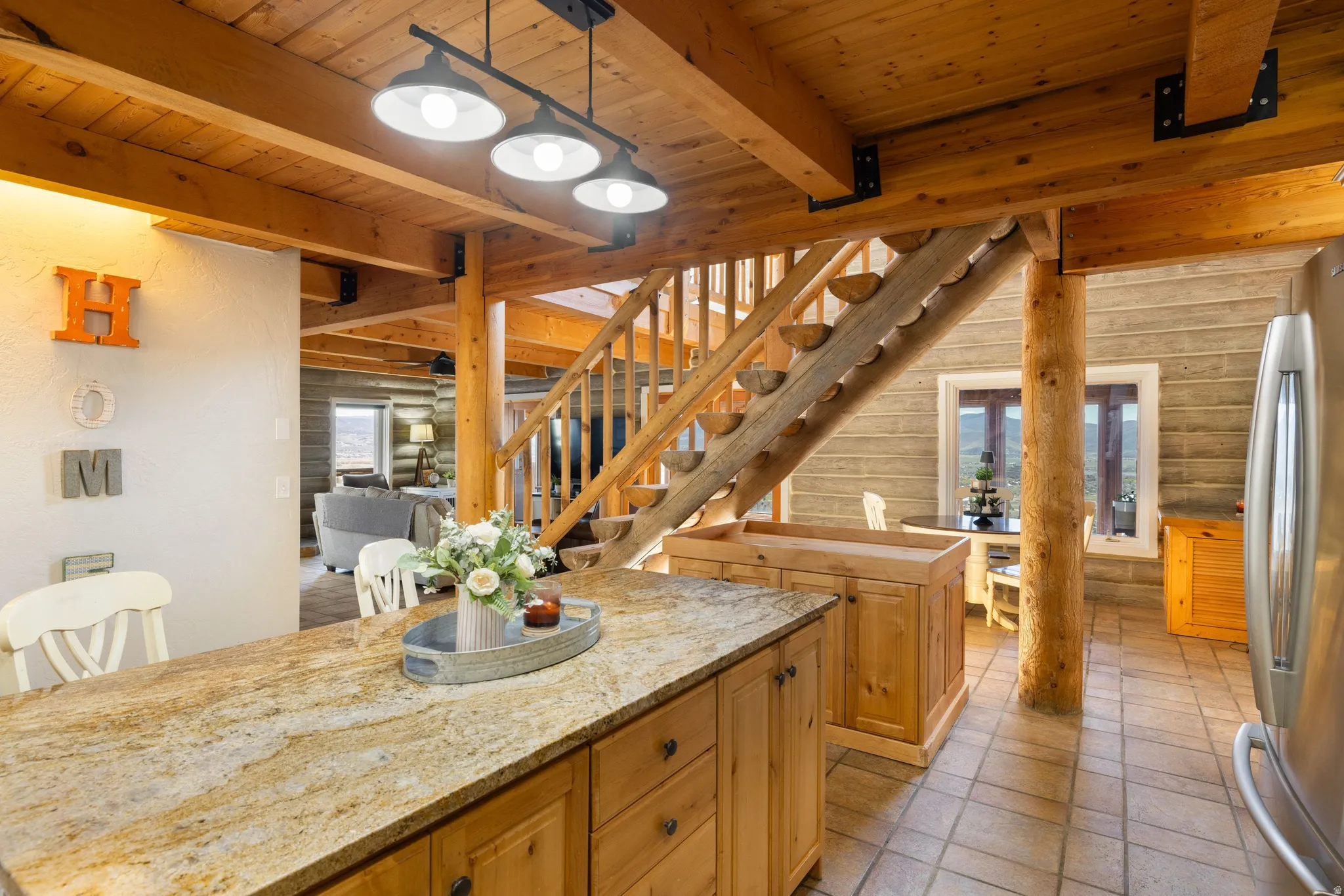 Kitchen featuring log walls, freestanding refrigerator, a kitchen island, a wooden ceiling with exposed beams, and wood finish cabinets