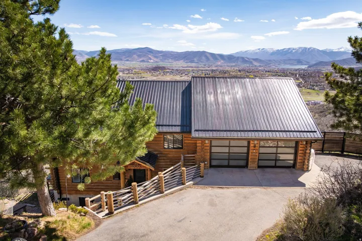 View of front of home with log siding, driveway, a metal roof, and a mountain view