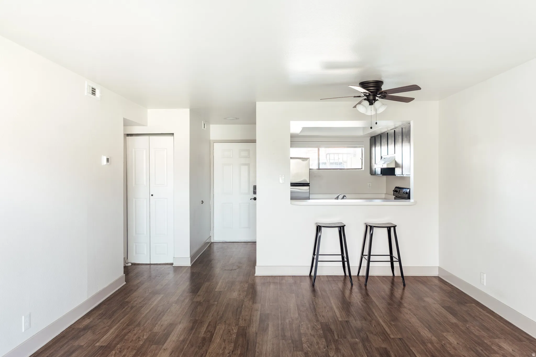 Unfurnished living room featuring ceiling fan and dark wood finished floors