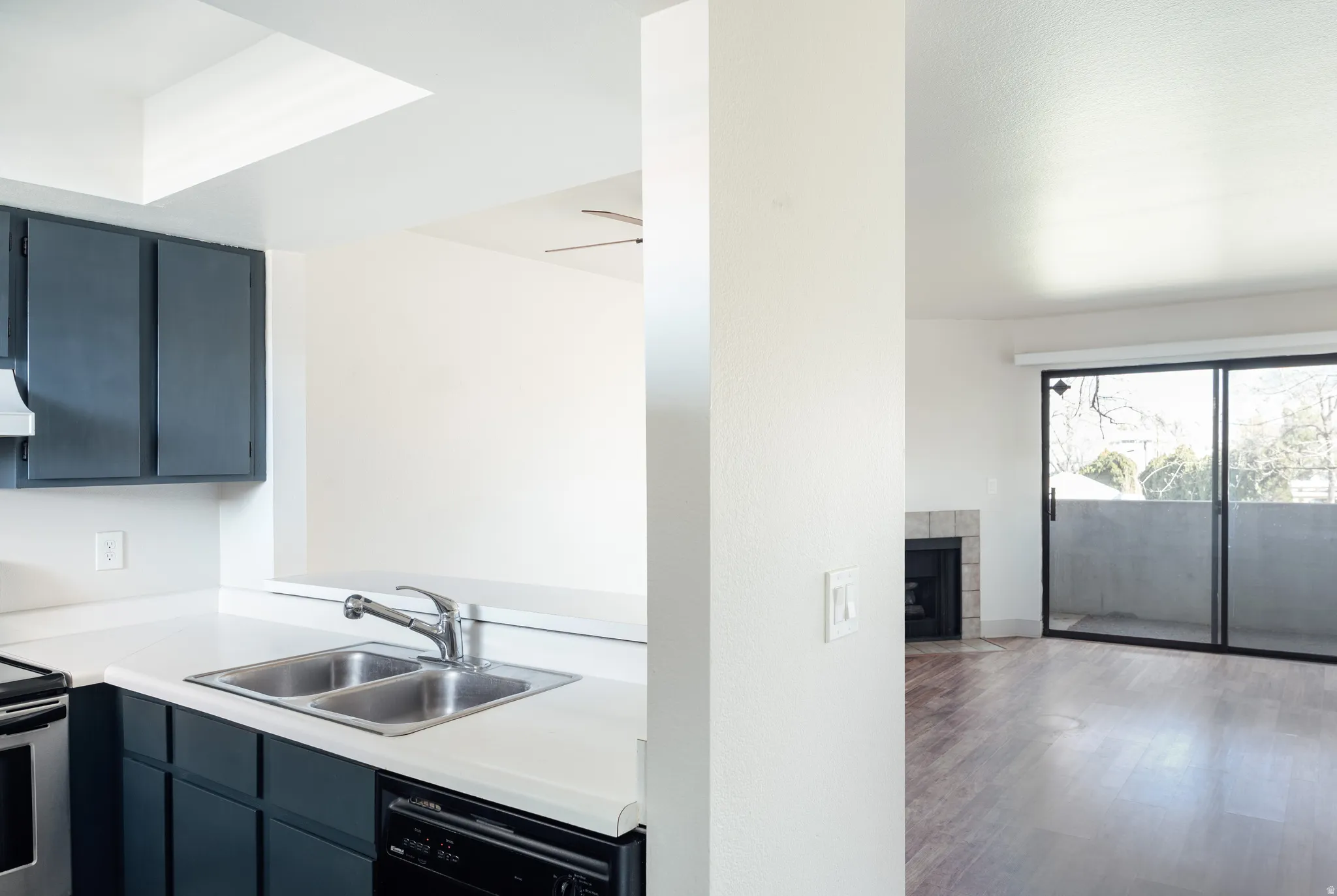 Kitchen with light countertops, blue cabinets, range with electric stovetop, dishwasher, and wood finished floors