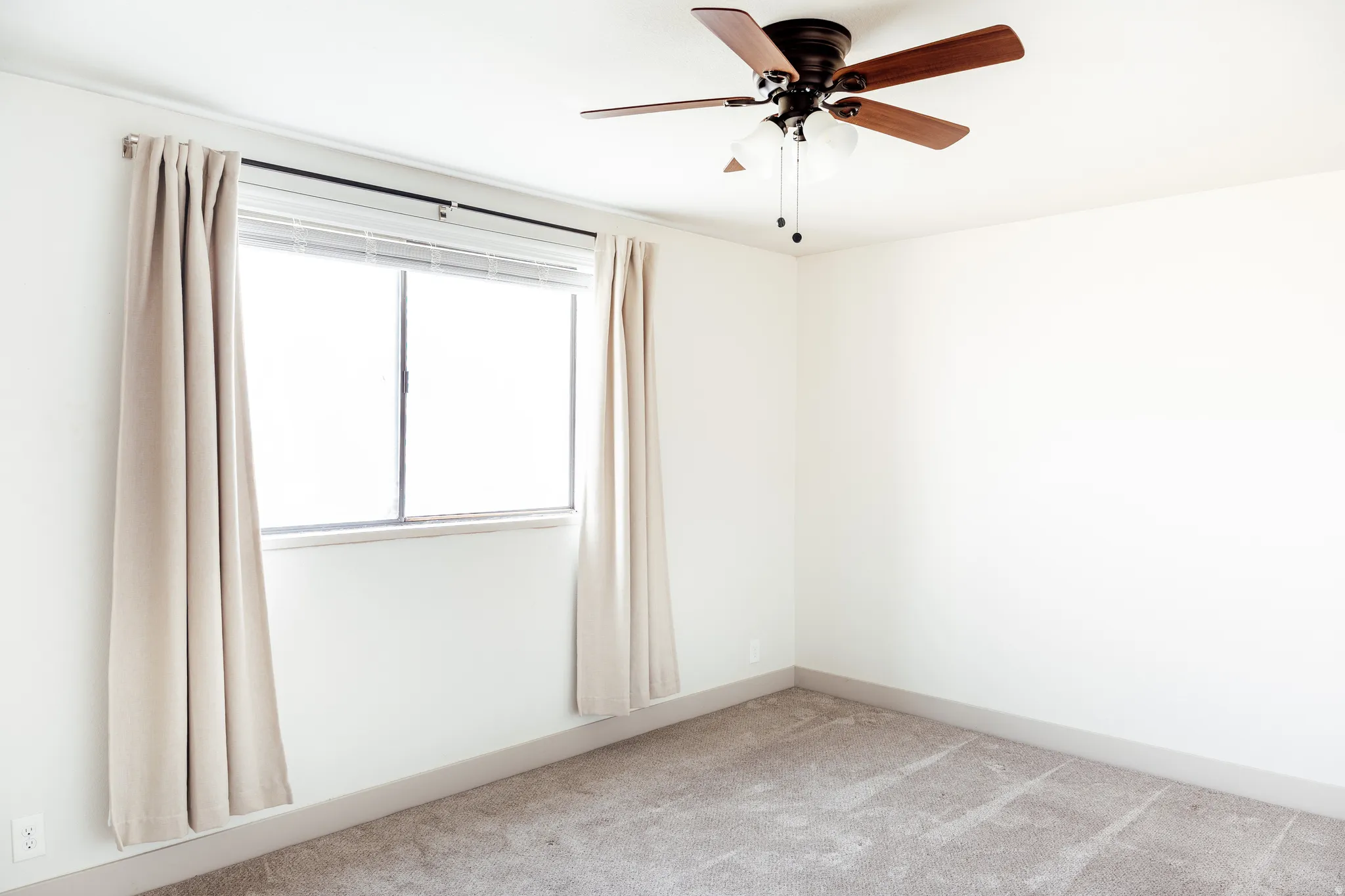 Spare room featuring light carpet and a ceiling fan