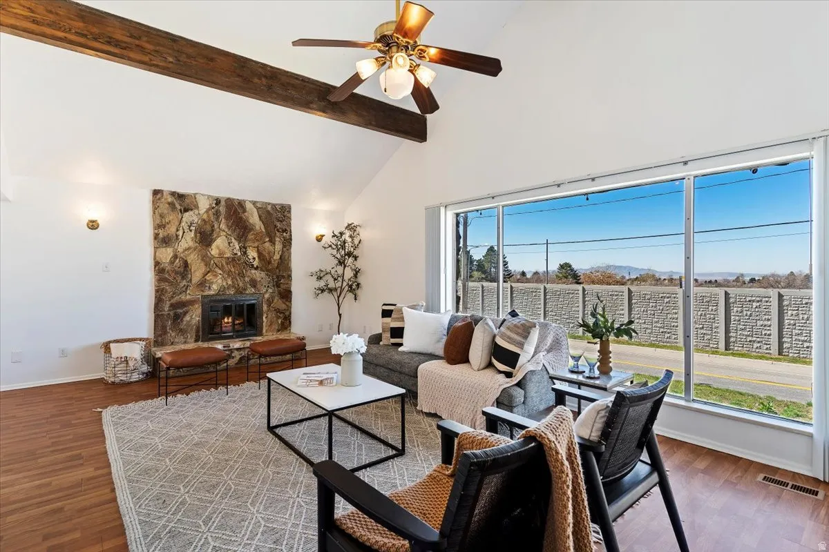 Living room with ceiling fan, a fireplace, lofted ceiling, and dark wood-style floors