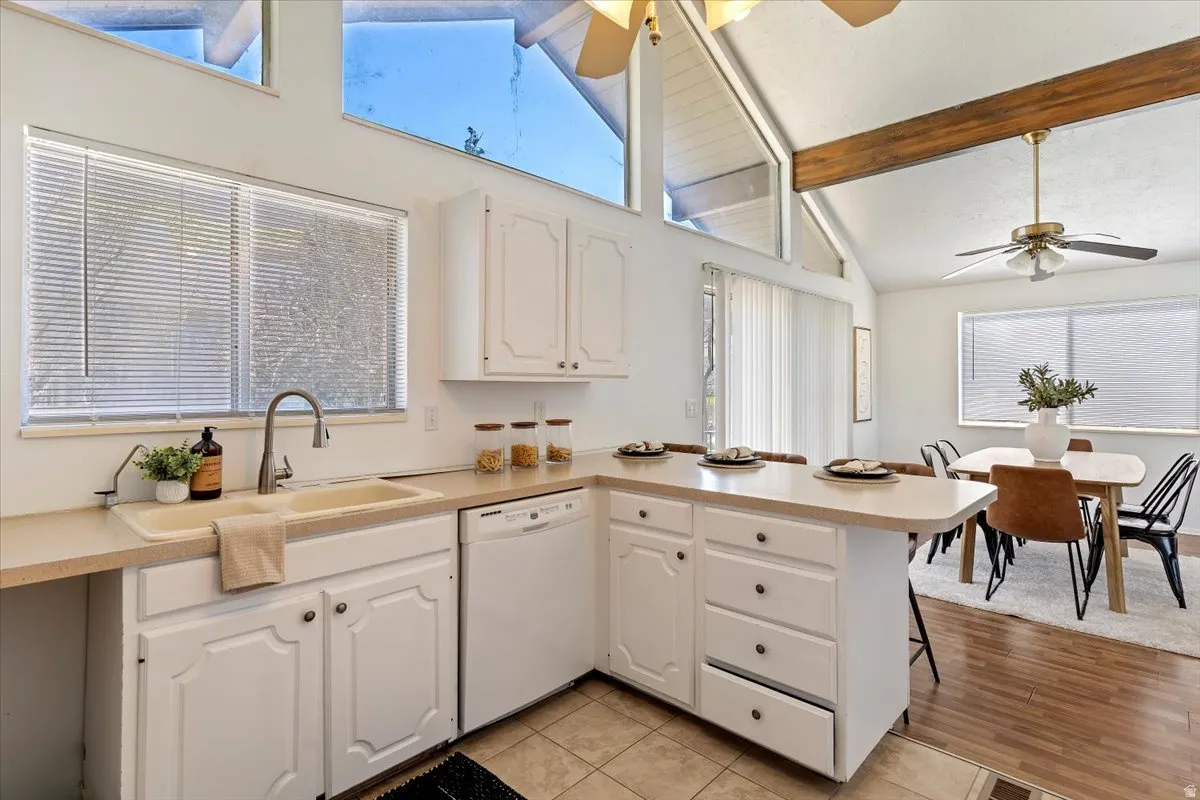 Kitchen featuring a peninsula, light countertops, a kitchen bar, white cabinetry, and ceiling fan