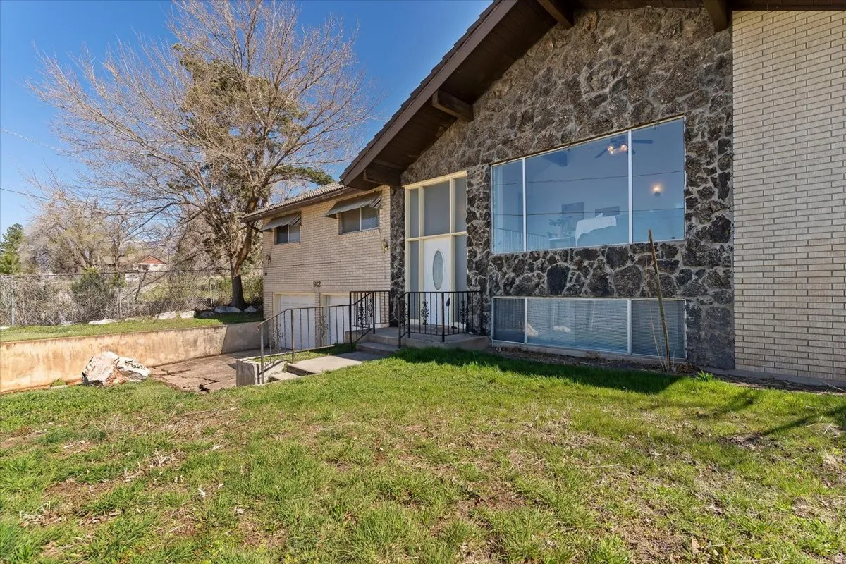 Back of property with a garage, stone siding, a yard, and brick siding