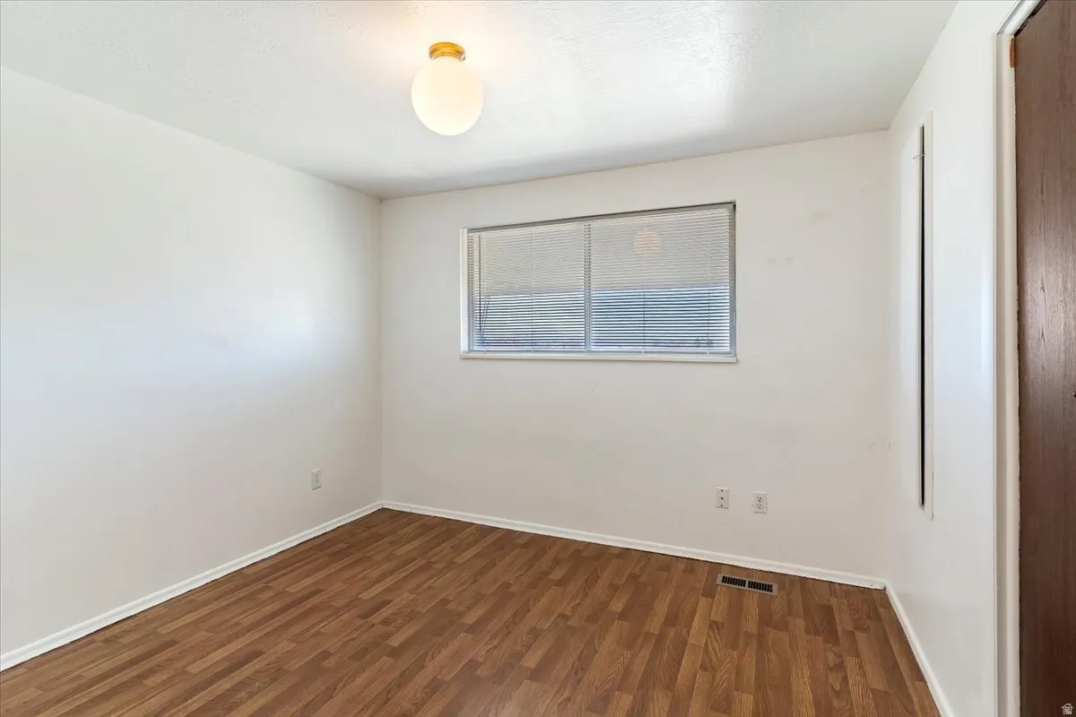 Unfurnished room featuring dark wood-style floors and baseboards