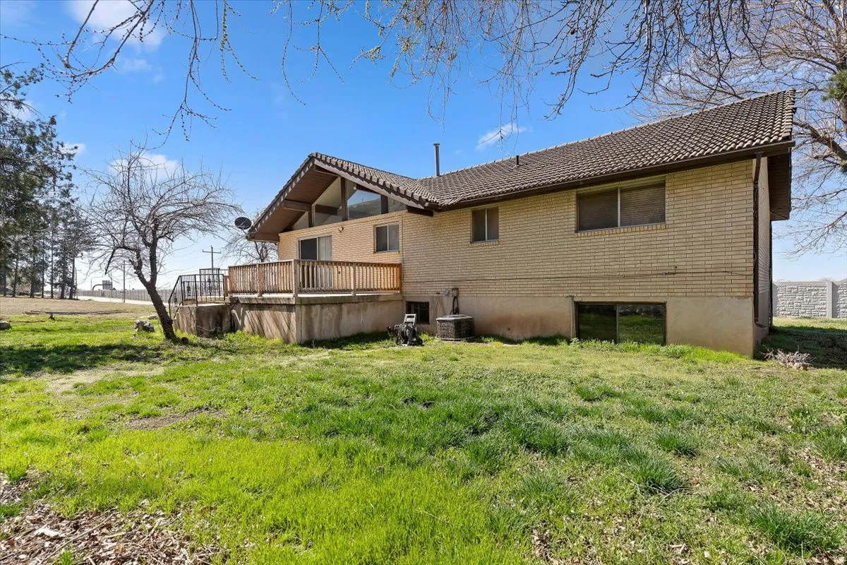 Back of house featuring a deck, a yard, and brick siding