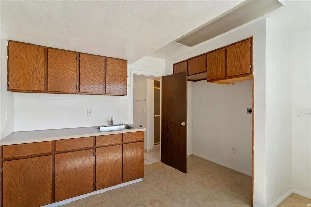 Kitchen with wood finish cabinets, light countertops, a textured ceiling, and light tile patterned floors