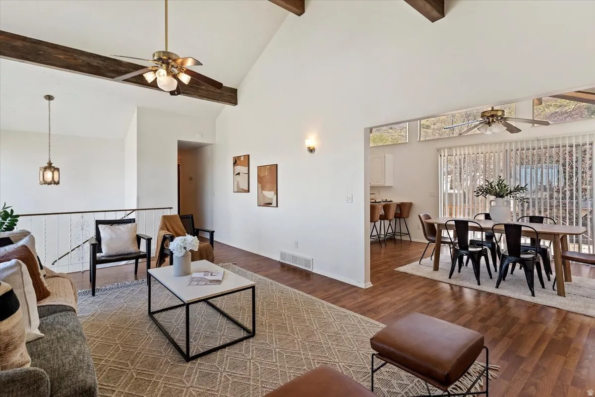 Living area with ceiling fan, dark wood-style floors, and lofted ceiling