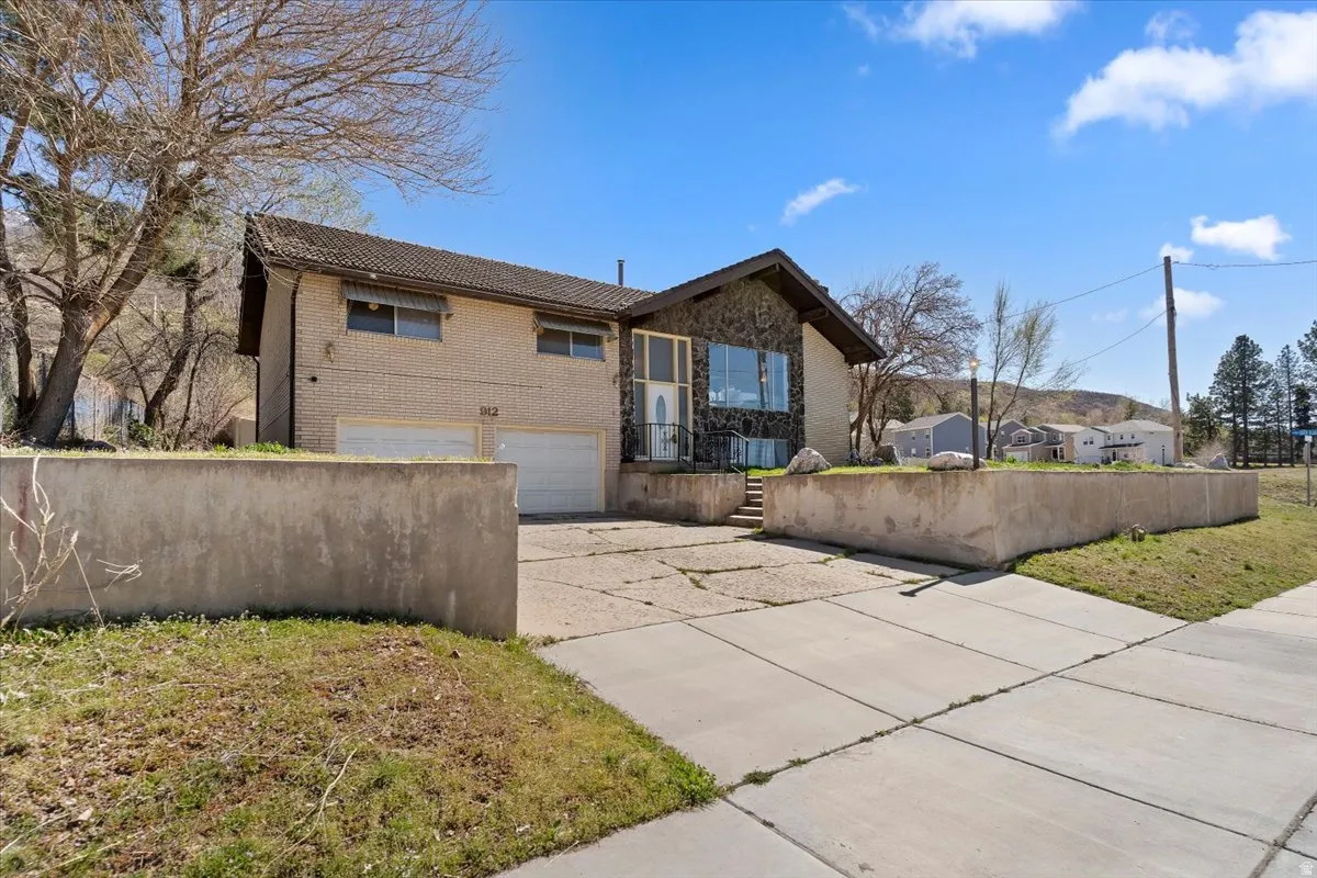 View of front of home featuring a garage, concrete driveway, brick siding, and a tiled roof