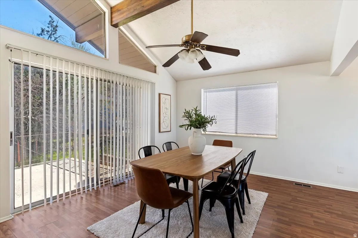 Dining space featuring dark wood-type flooring, a ceiling fan, and lofted ceiling