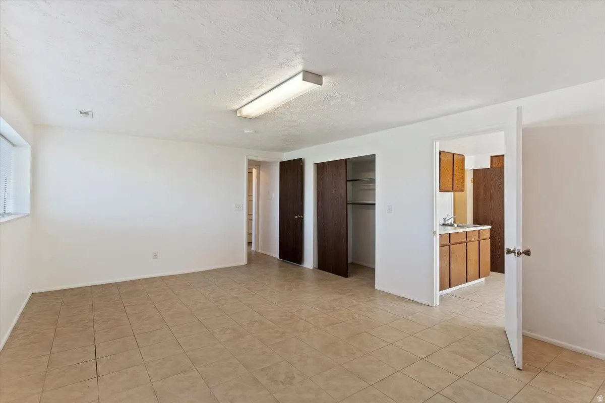 Unfurnished bedroom featuring a closet, a textured ceiling, and light tile patterned floors