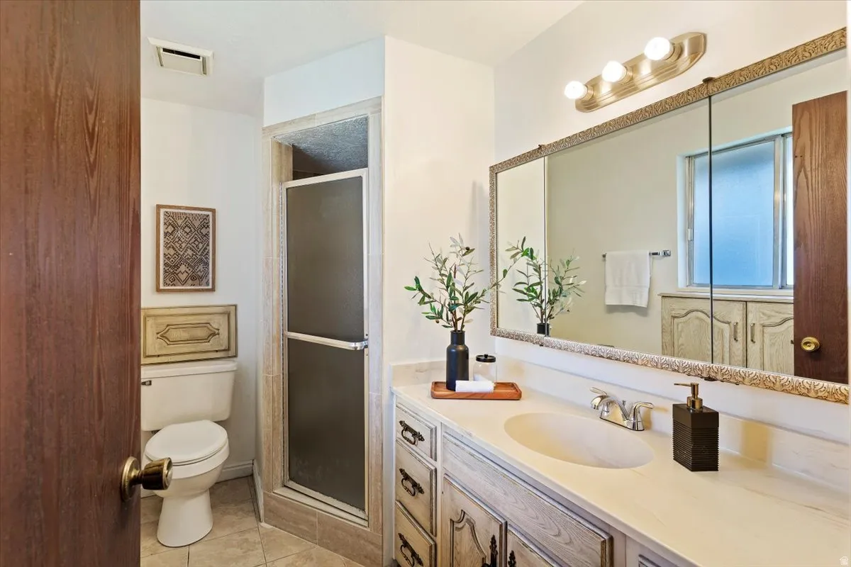 Bathroom with a stall shower, vanity, and light tile patterned flooring