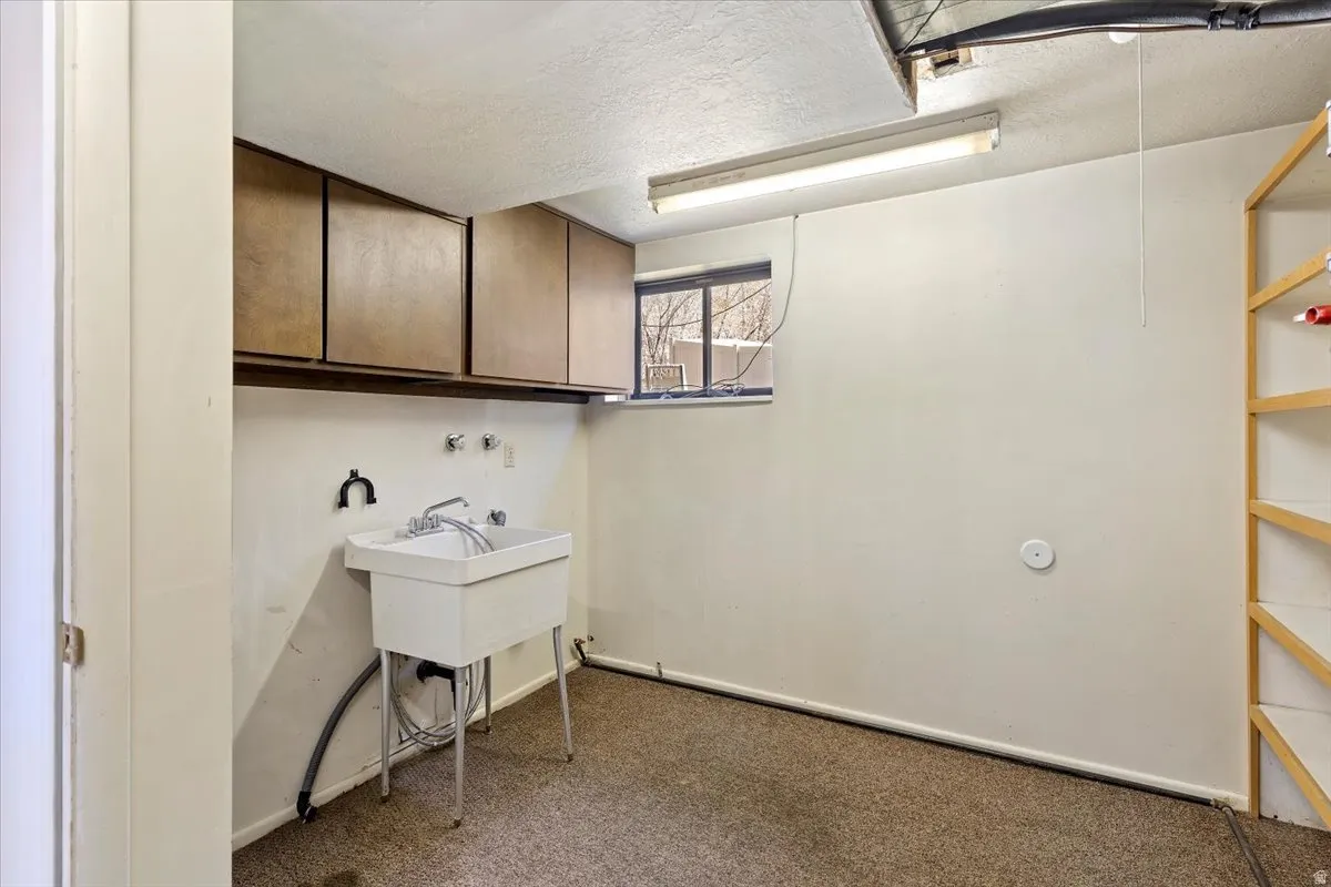 Laundry room with a textured ceiling and dark carpet