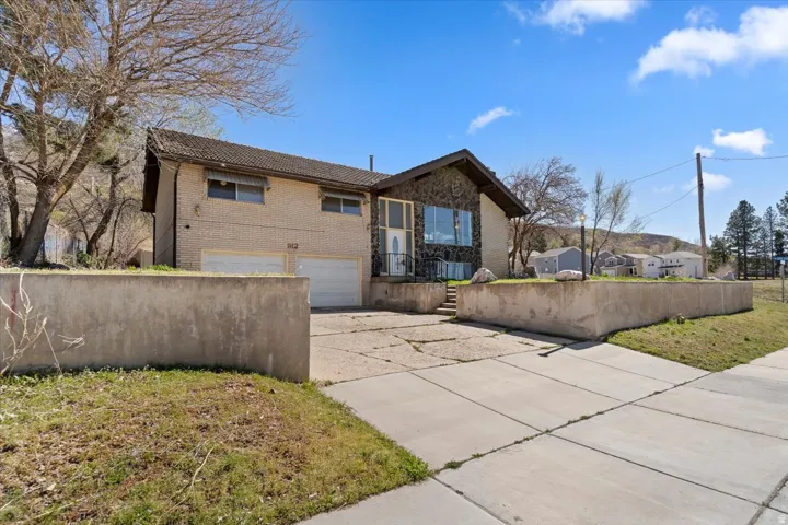 View of front of home featuring a garage, concrete driveway, brick siding, and a tiled roof