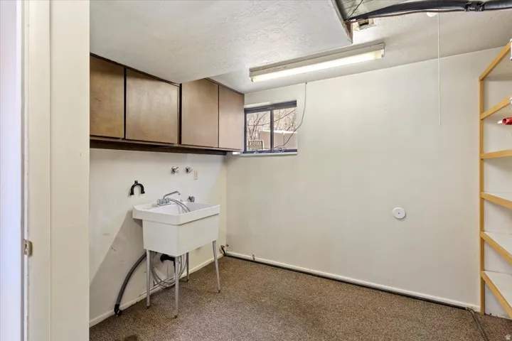 Laundry room with a textured ceiling and dark carpet
